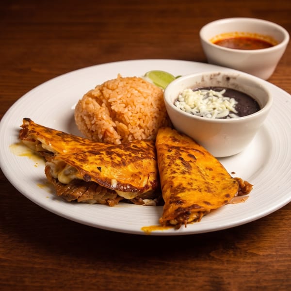 Plate of golden folded quesadillas with orange rice, black beans, lime, and salsa on a wooden table.
